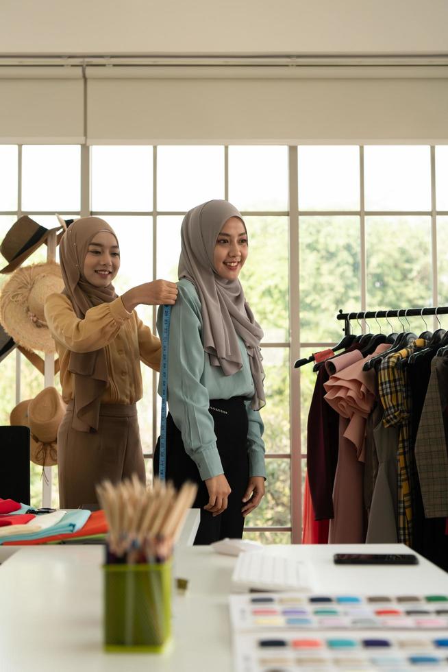ambas mujeres musulmanas tienen un pequeño negocio en sus propios hogares. es el diseño y confección de ropa. foto