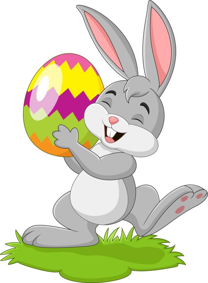 Cartoon little rabbit holding easter egg in the grass vector