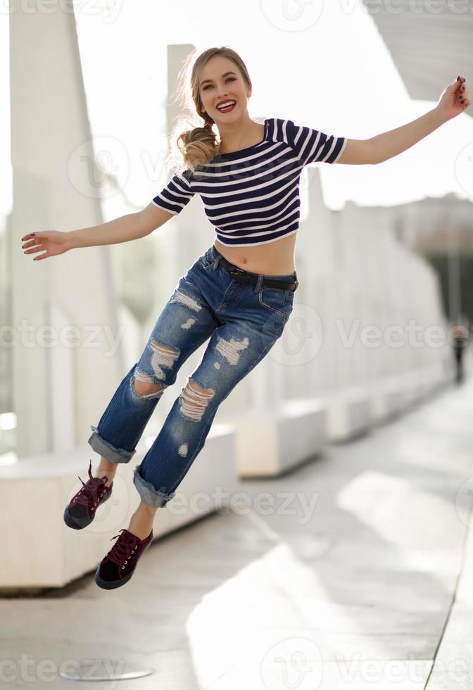 Funny blonde woman jumping in urban background. photo