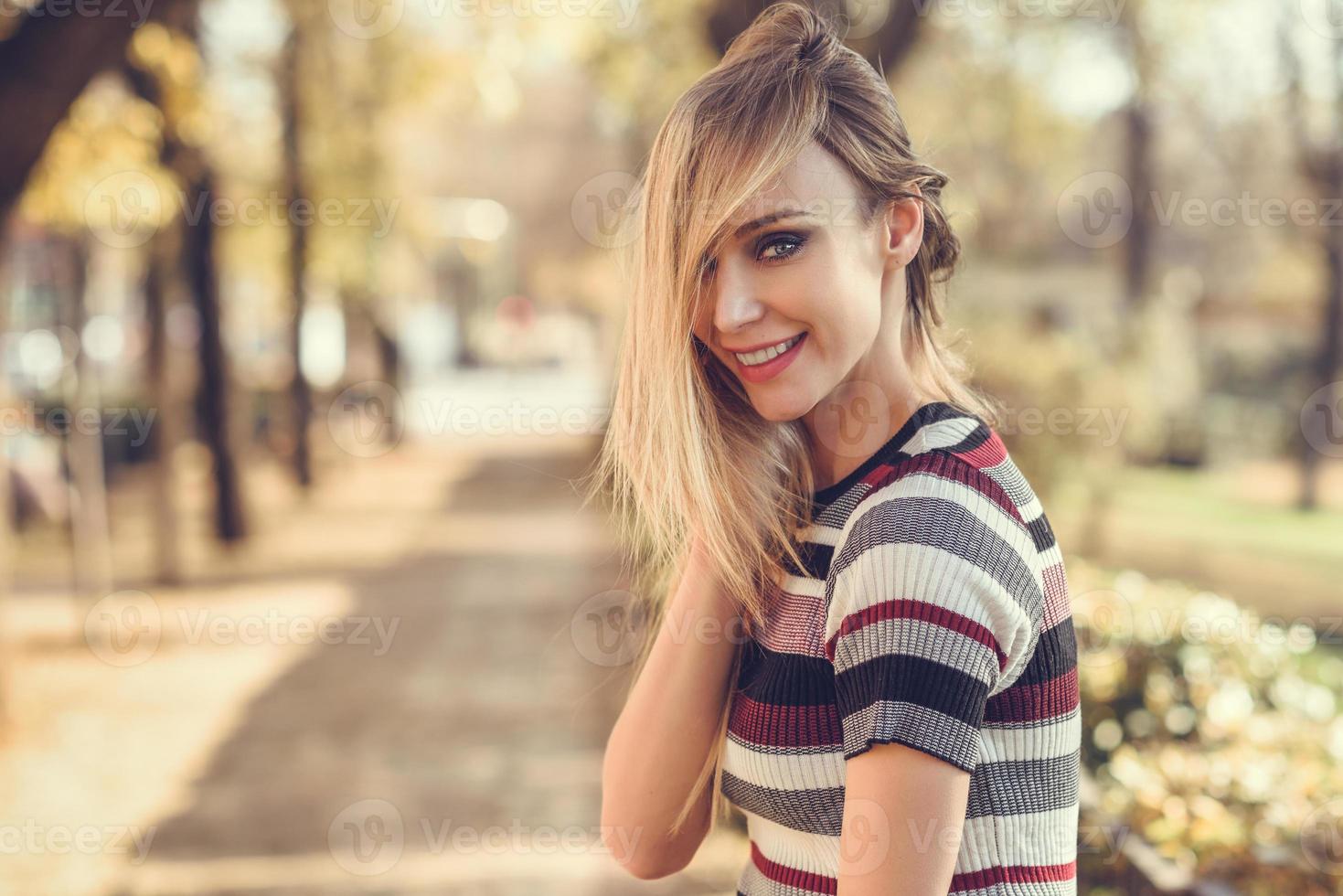 Young blonde woman standing in the street moving her hair photo
