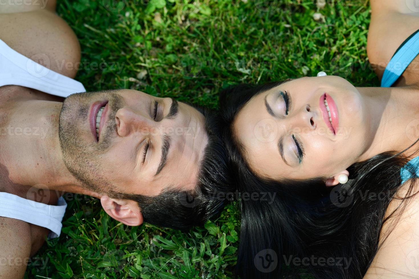 feliz pareja sonriente recostada sobre la hierba verde foto