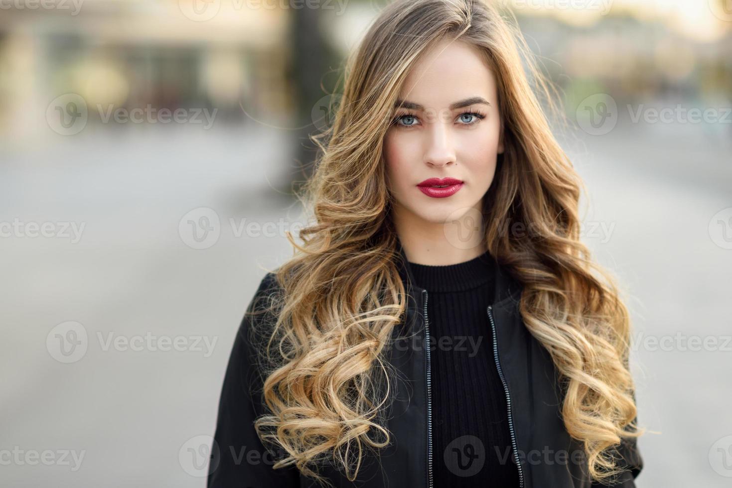 Young blonde girl with beautiful blue eyes wearing black jacket. photo
