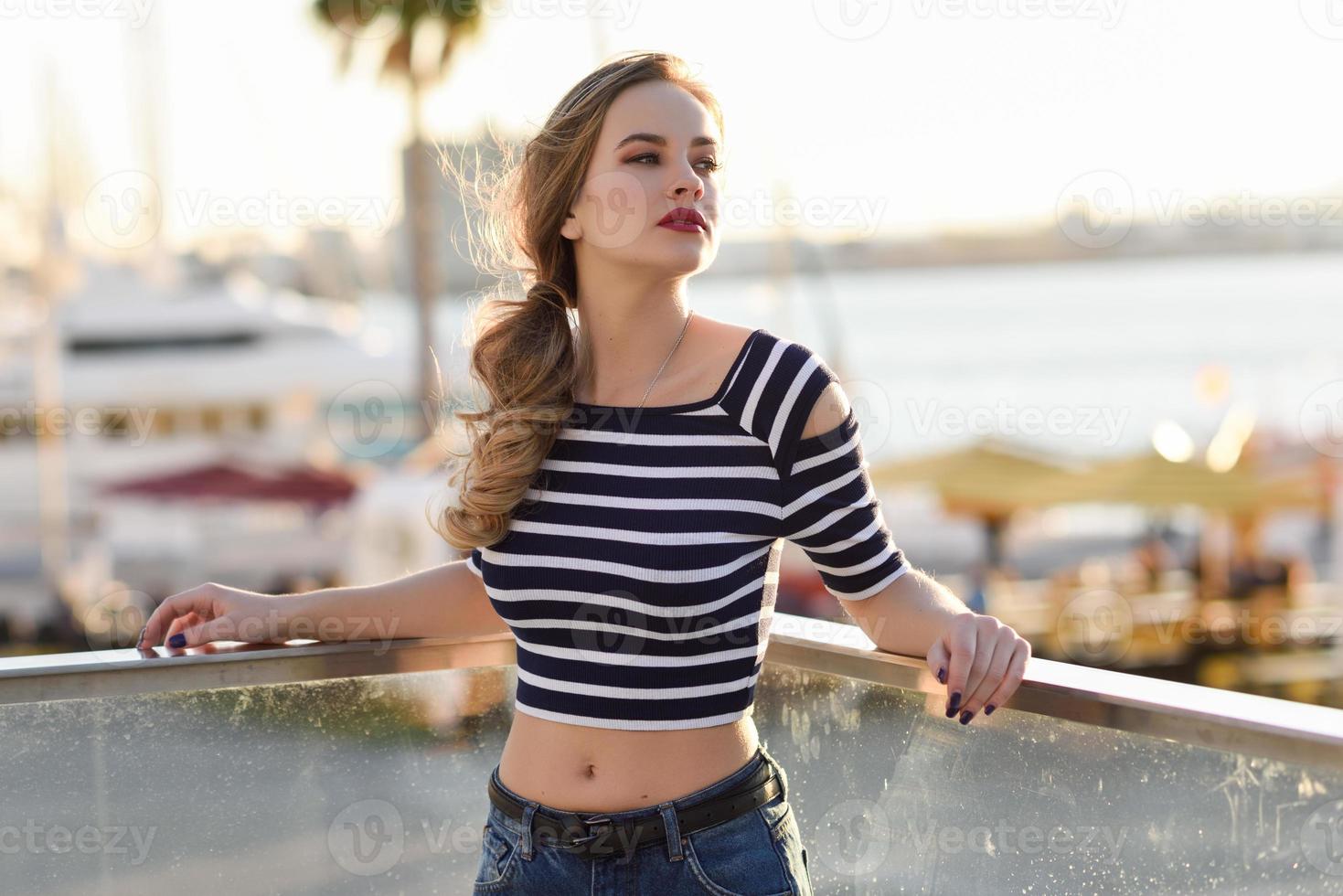 Blonde woman, model of fashion, sitting in urban background. photo