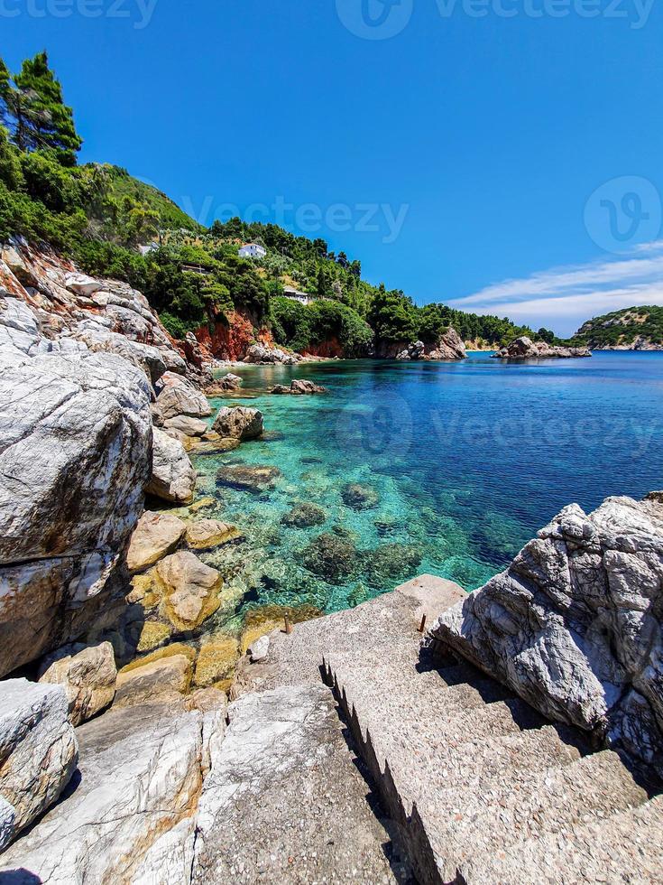 vista prístina de la bahía de una isla de grecia con escalones de concreto que conducen al agua. foto