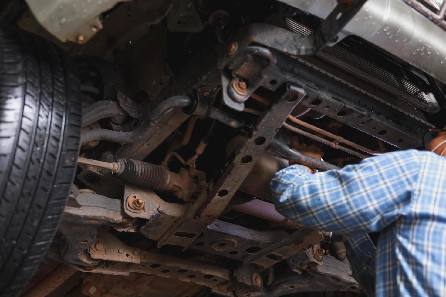 The mechanic is checking the undercarriage of the car. photo