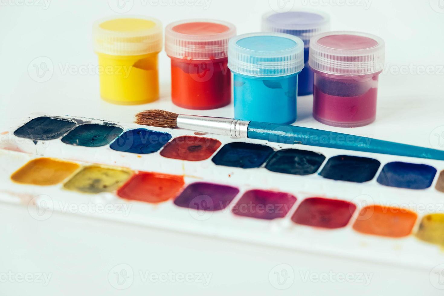 Colorful gouache paints and brush for painting on white background photo
