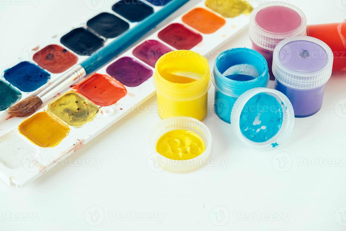 Colorful gouache paints and brush for painting on white background photo