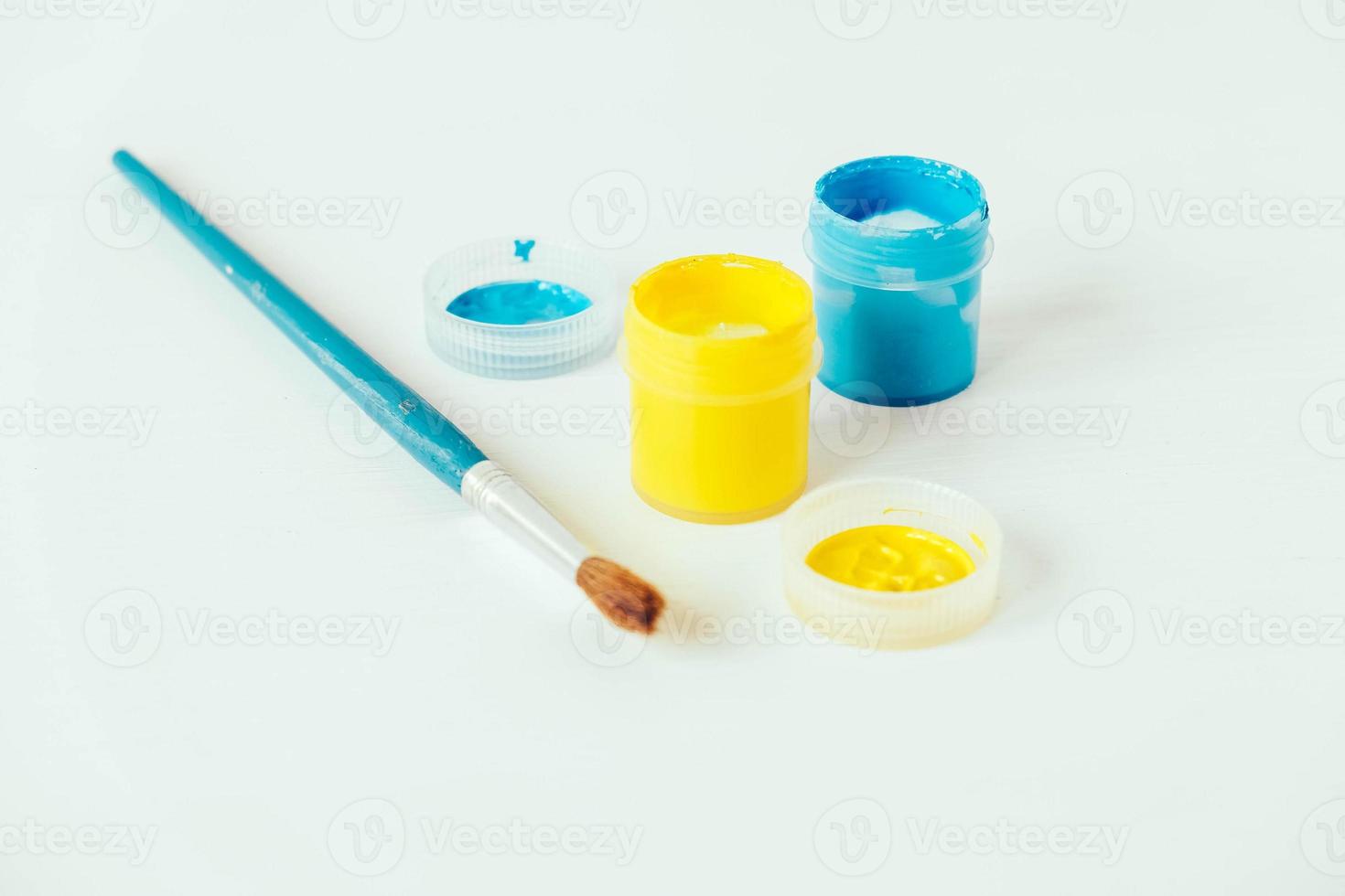 Colorful gouache paints and brush for painting on white background photo