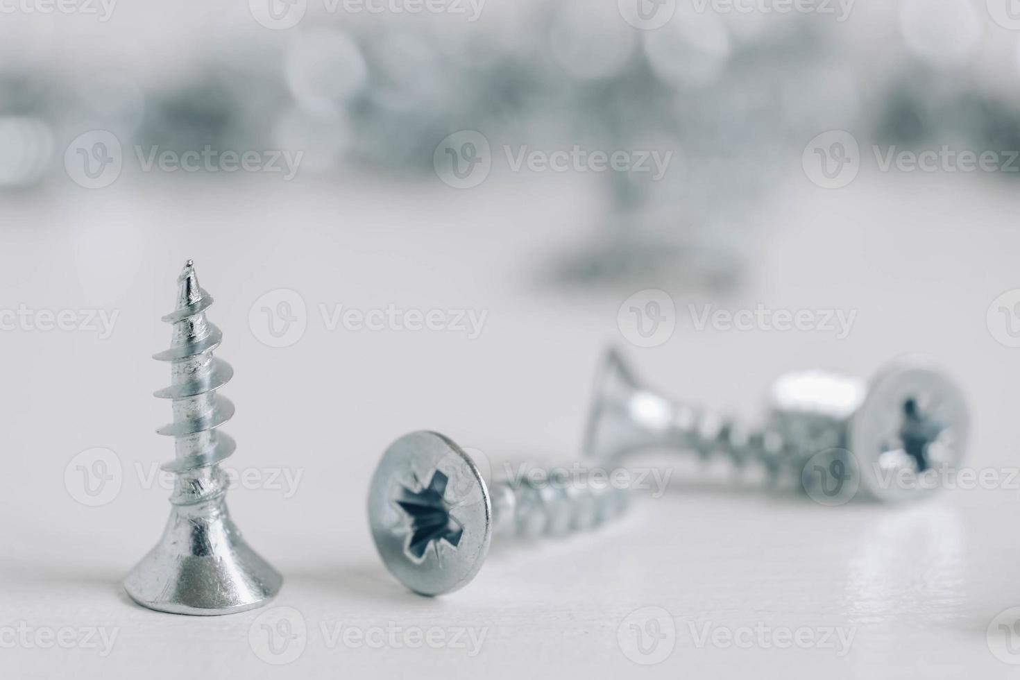 Metal tapping screws for wood on white wooden background photo
