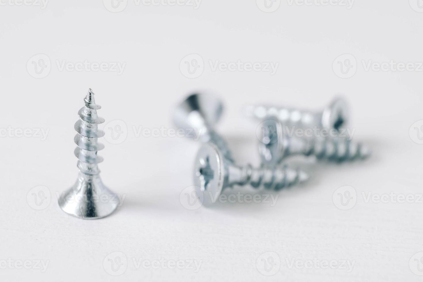 Metal tapping screws for wood on white wooden background photo