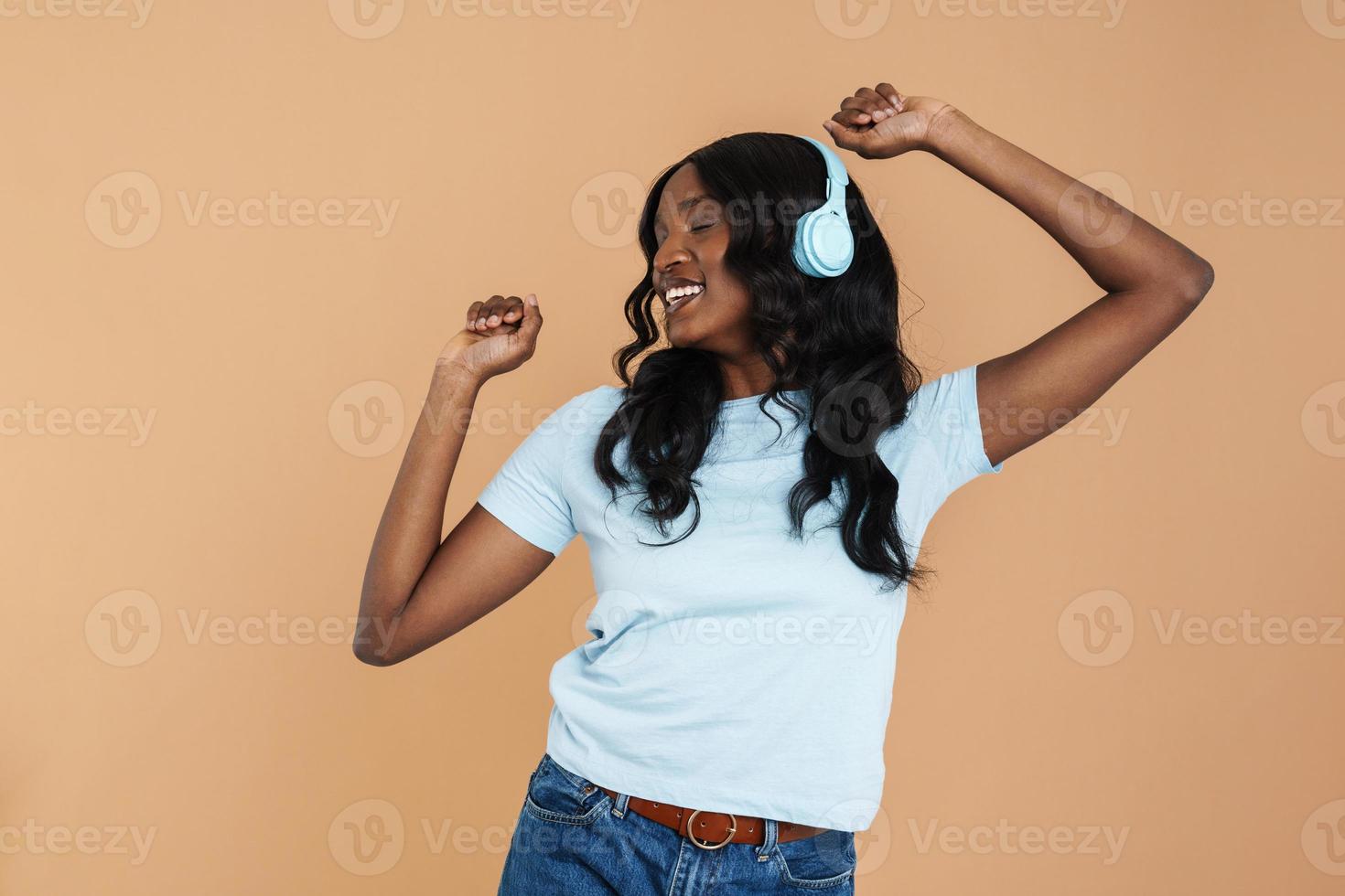 mujer africana sonriente bailando y cantando con auriculares foto