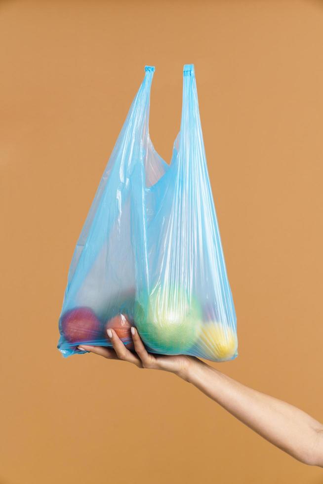 Woman holding plastic trash bag with fruit photo