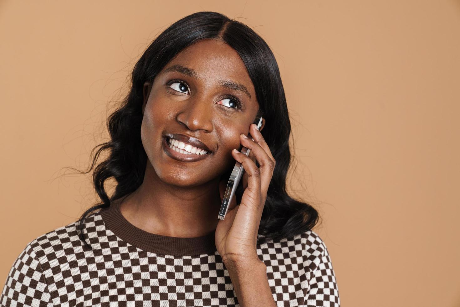 Positive African woman talking on the phone looking off to the side photo