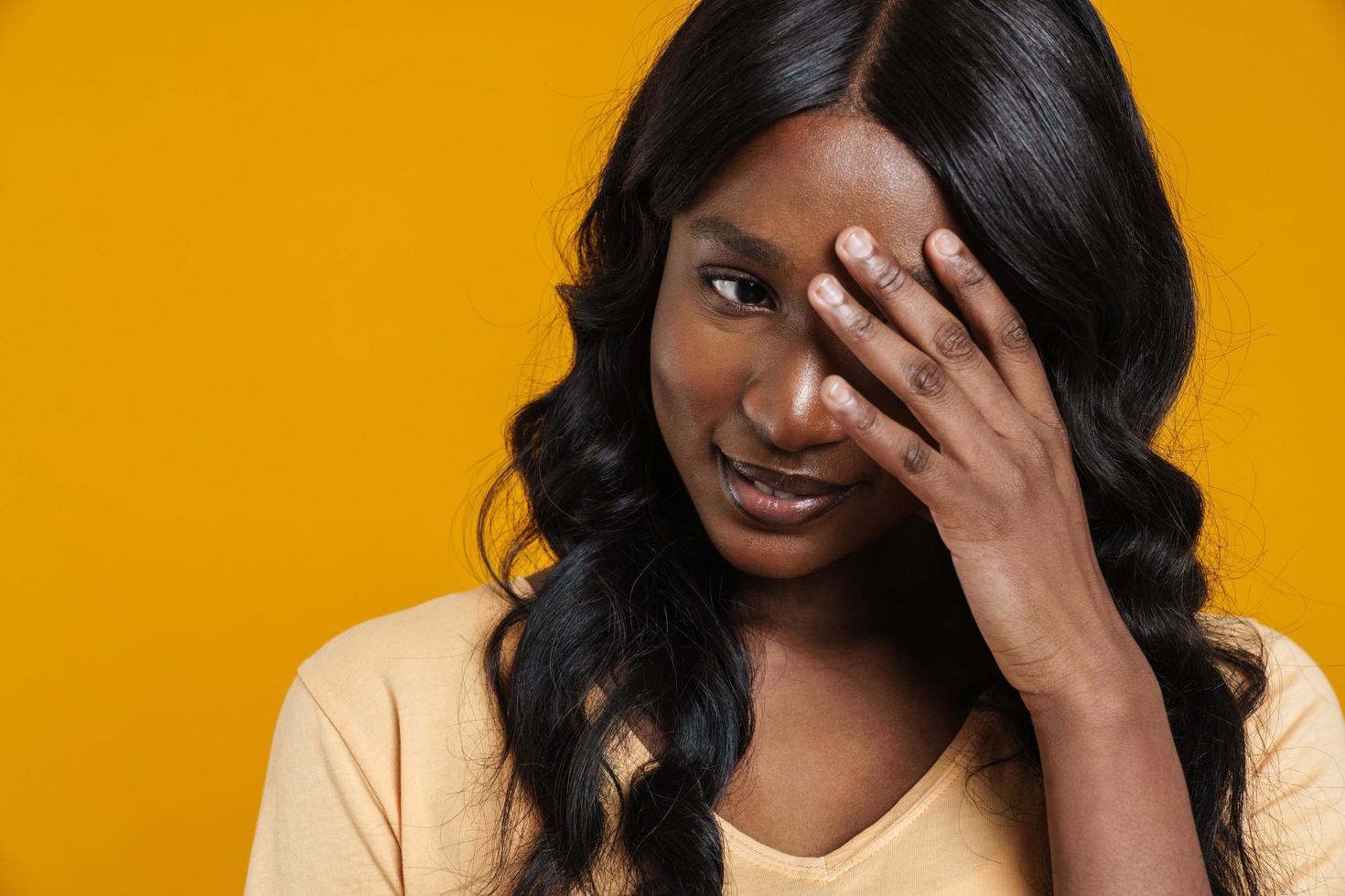 Confused African woman covering her eye with hand photo