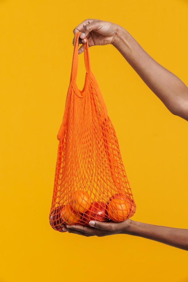 Female hands holding reusable orange fruit bag up to the camera photo