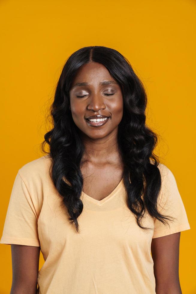 retrato de una mujer africana sonriente parada con los ojos cerrados foto