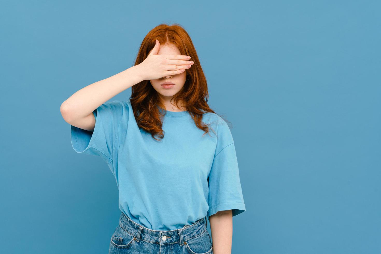 Jengibre joven mujer vistiendo camiseta que cubre su rostro foto