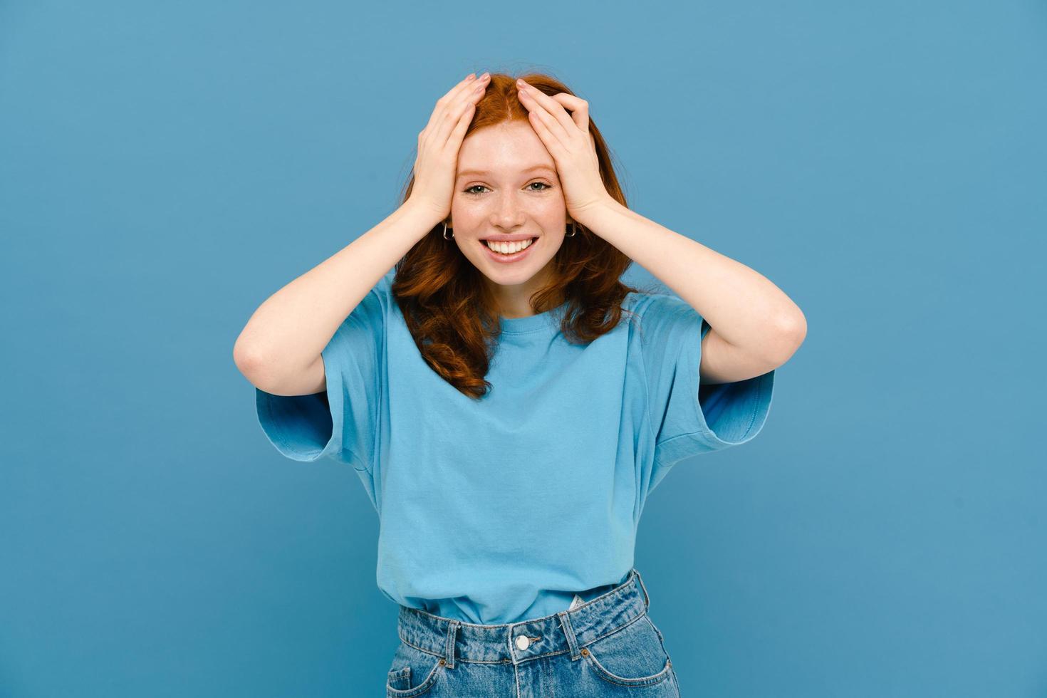 Young ginger-haired woman wearing a blue t-shirt smiling at camera photo