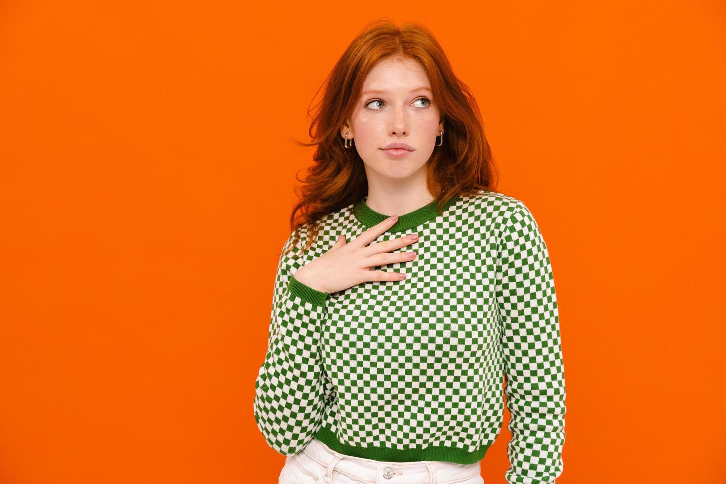 Puzzled woman in plaid sweater looking aside photo