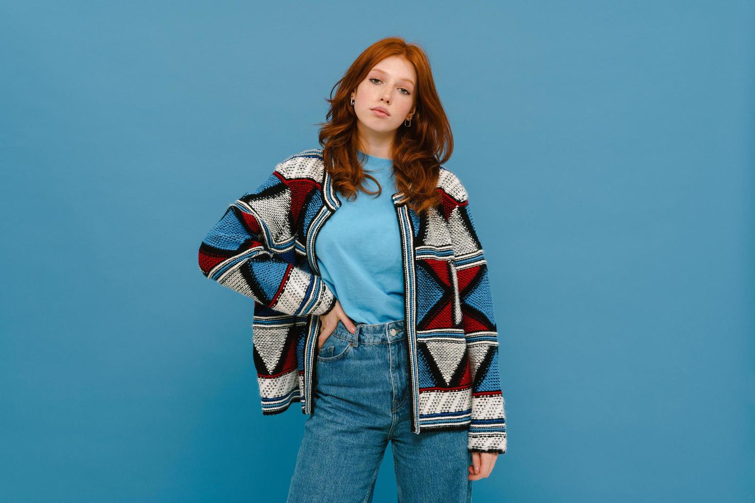 mujer joven de jengibre posando en suéter de punto multicolor foto