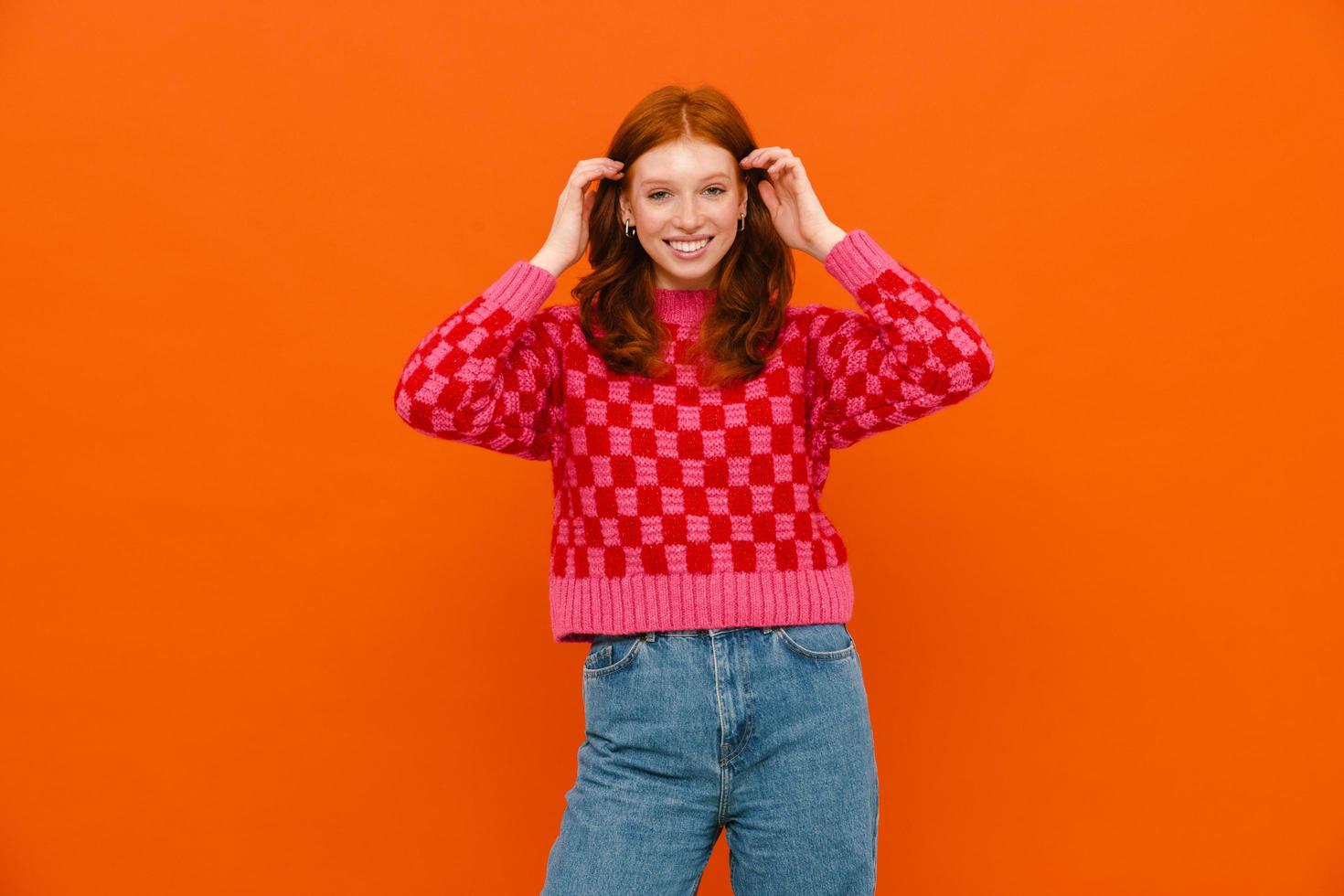 Young woman with ginger hair in plaid sweater smiling at camera photo