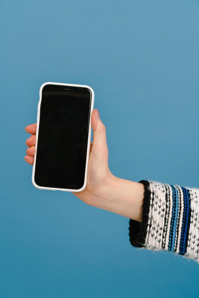 White young woman in multicolored sweater showing her cellphone photo