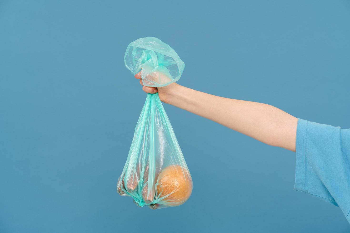 mujer joven con camiseta sosteniendo una bolsa de basura de plástico foto