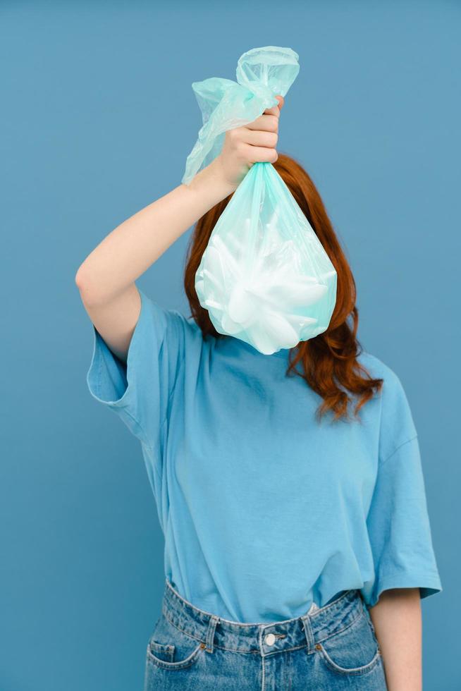 Young woman wearing t-shirt holding plastic trash bag photo