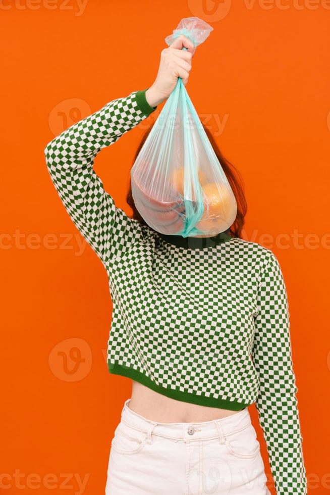 Young woman wearing plaid sweater holding plastic trash bag photo