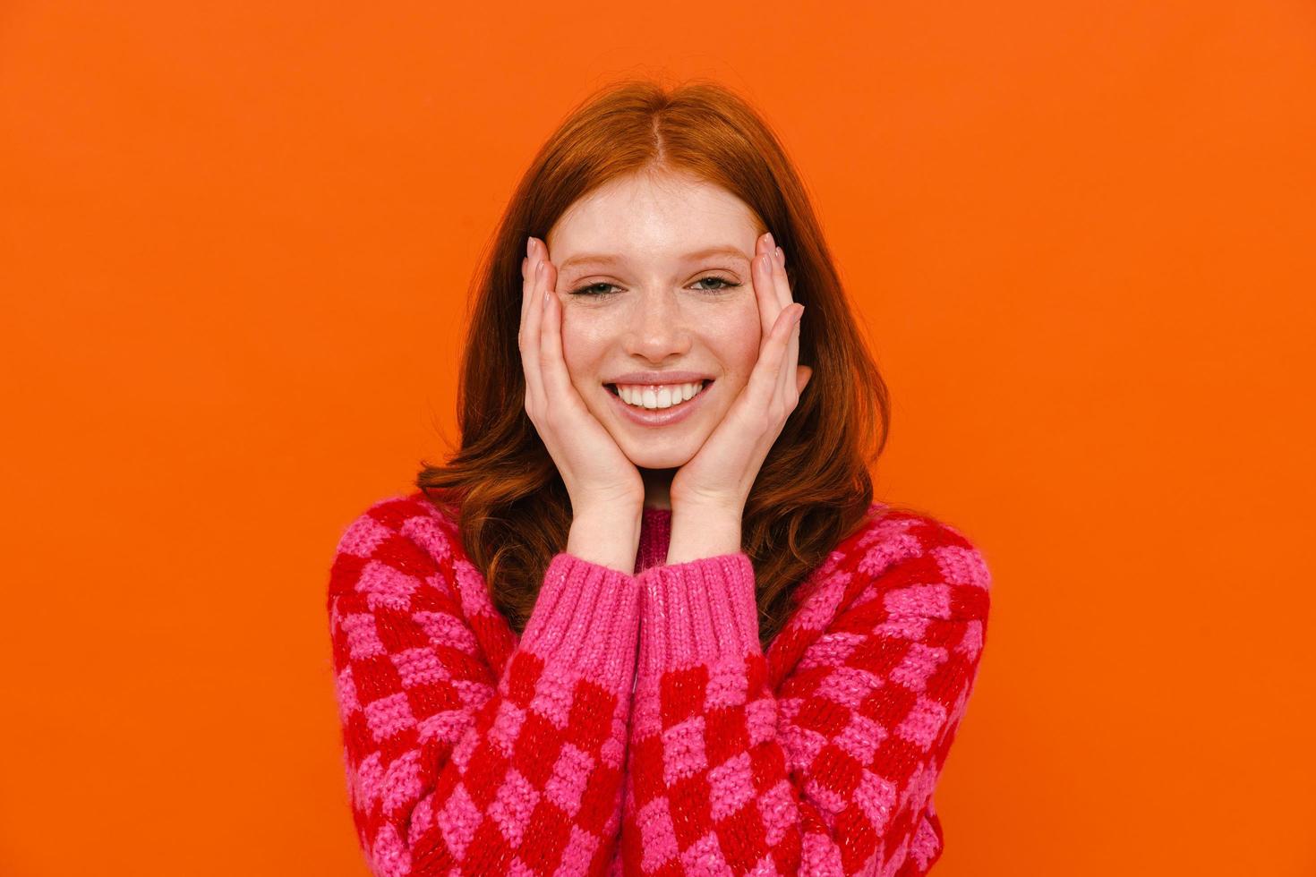 Young ginger woman in plaid sweater smiling at camera photo