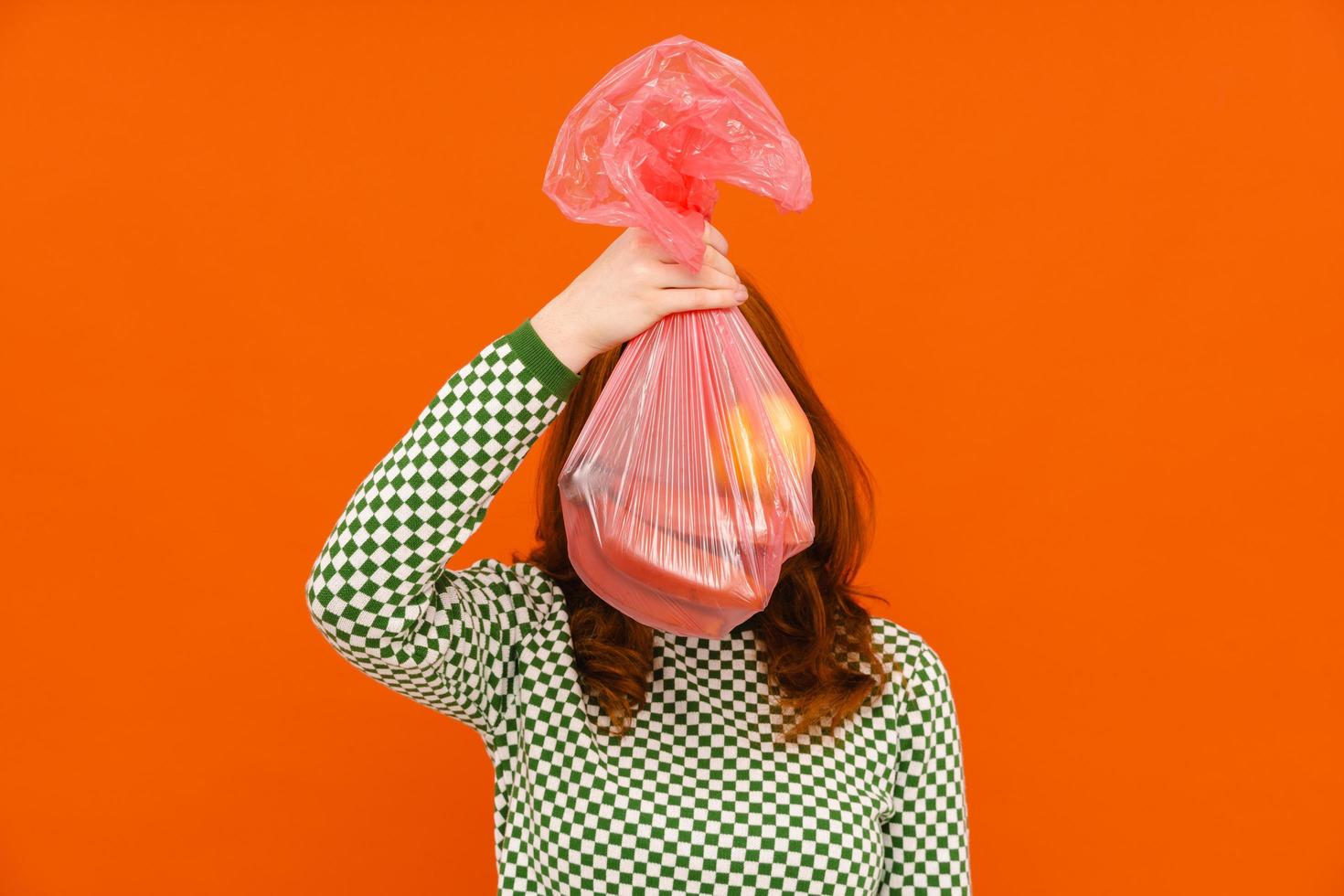 mujer joven con suéter a cuadros sosteniendo una bolsa de basura de plástico foto