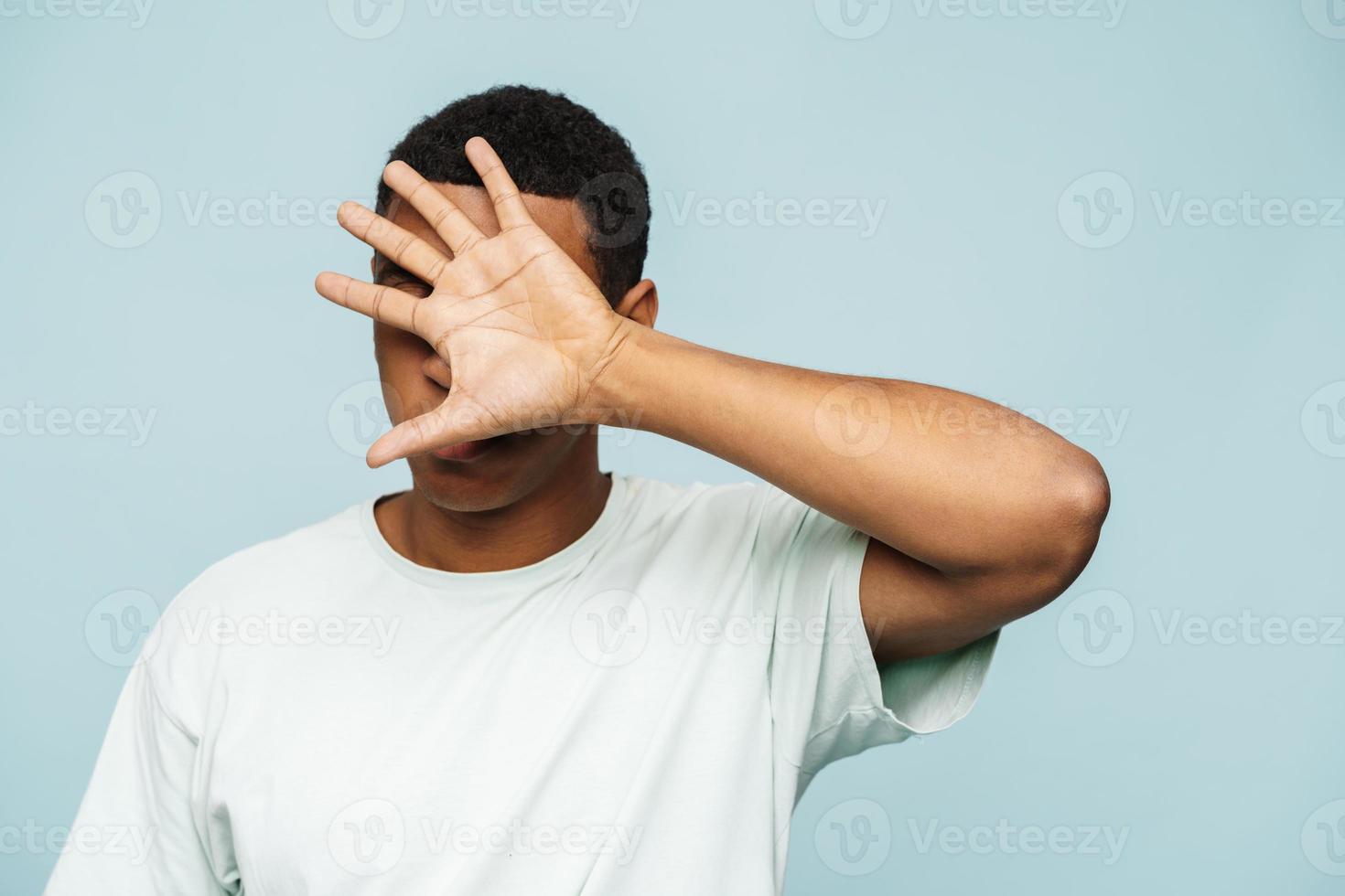 African man covering face with hand photo