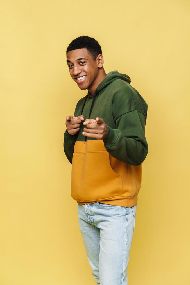 Positive African man in hoodie pointing fingers to the camera photo