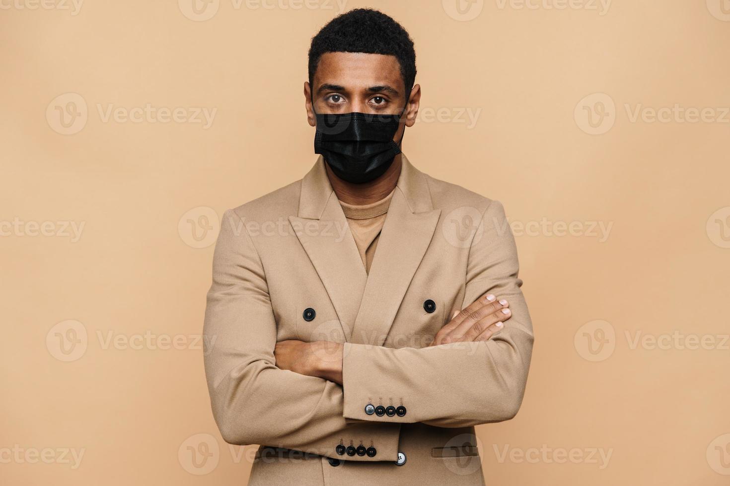 Serious African businessman in protective face mask looking straight into the camera photo