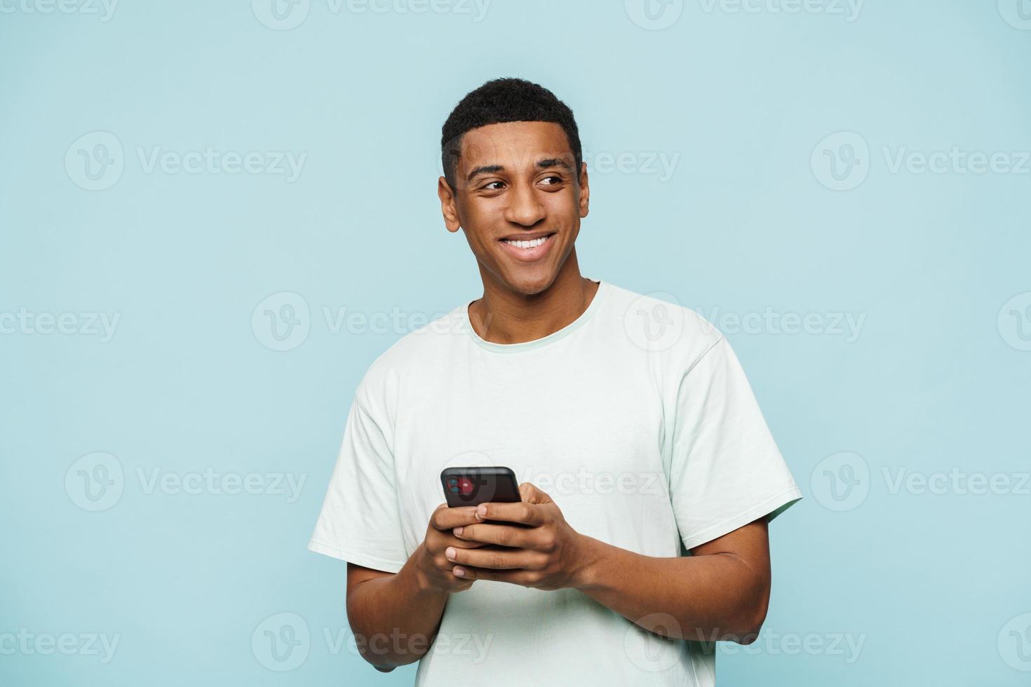 Smiling African man looking to the side and typing on his phone photo