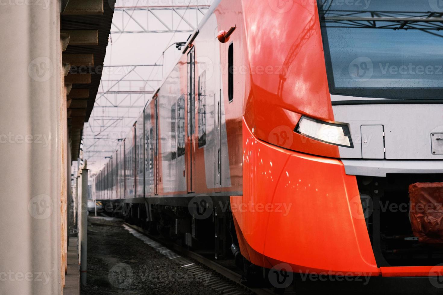 red with a gray high-speed commuter train departing from the railroad station photo