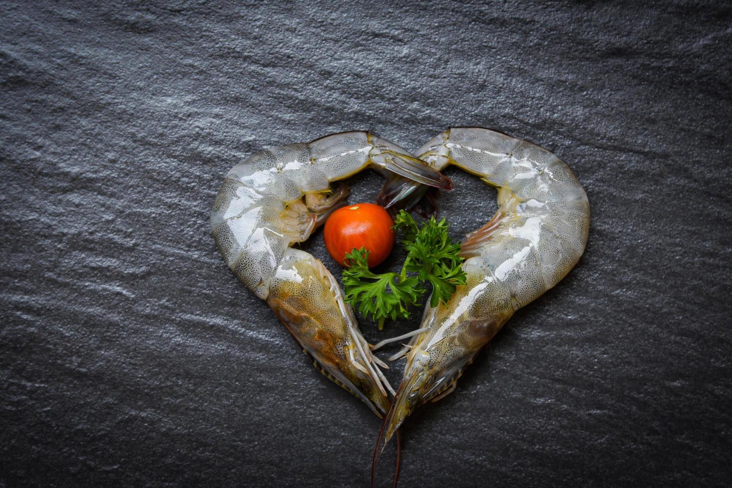 Mariscos dos camarones en forma de corazón langostinos crudos frescos sobre fondo oscuro foto