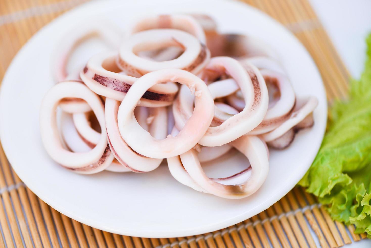 squid rings on white plate, Fresh squid cooked boiled with lettuce vegetable salad on wooden background photo