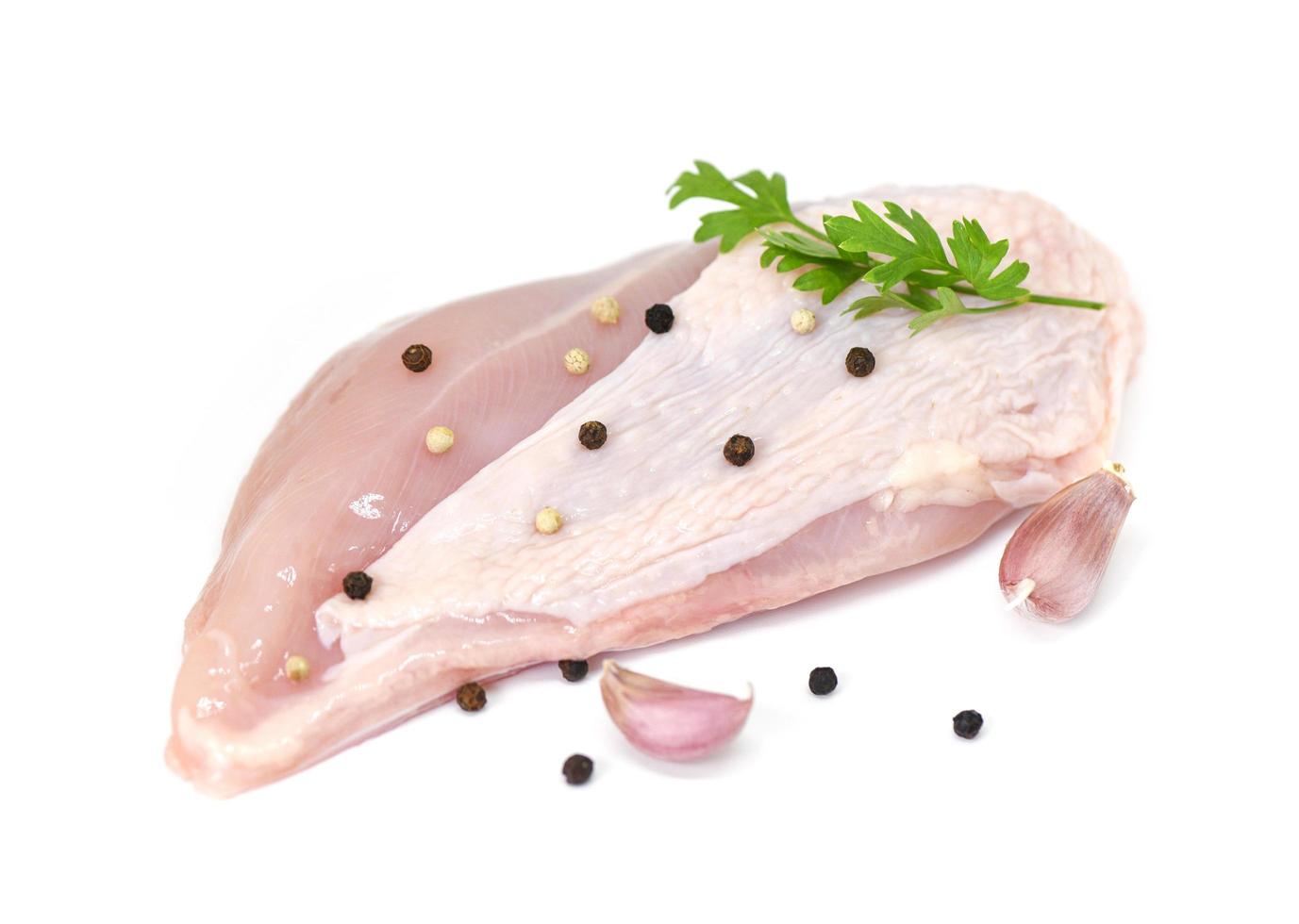 raw chicken breast with herbs and spices isolated on white background - Raw uncooked chicken meat marinated with ingredients for cooking food photo