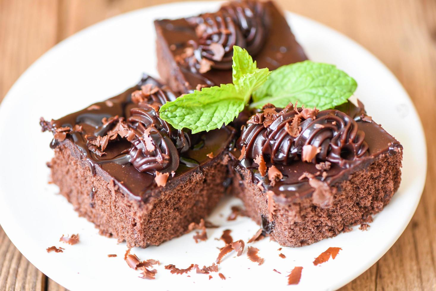 Cake chocolate delicious dessert served on the table - cake slice on white plate with topping chocolate and mint leaf photo