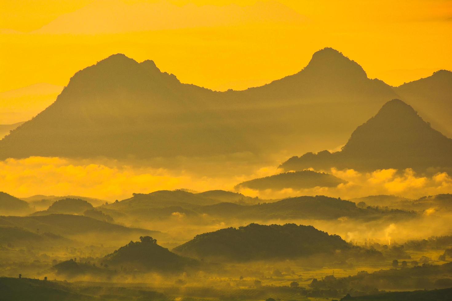 paisaje cordillera con niebla niebla amanecer en la mañana nublado sobre cielo amarillo en la montaña de la colina foto