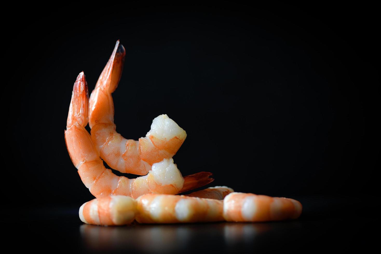 decorar la mesa de comedor comida hermosos camarones langostinos hervidos mariscos cocidos sobre fondo negro oscuro foto