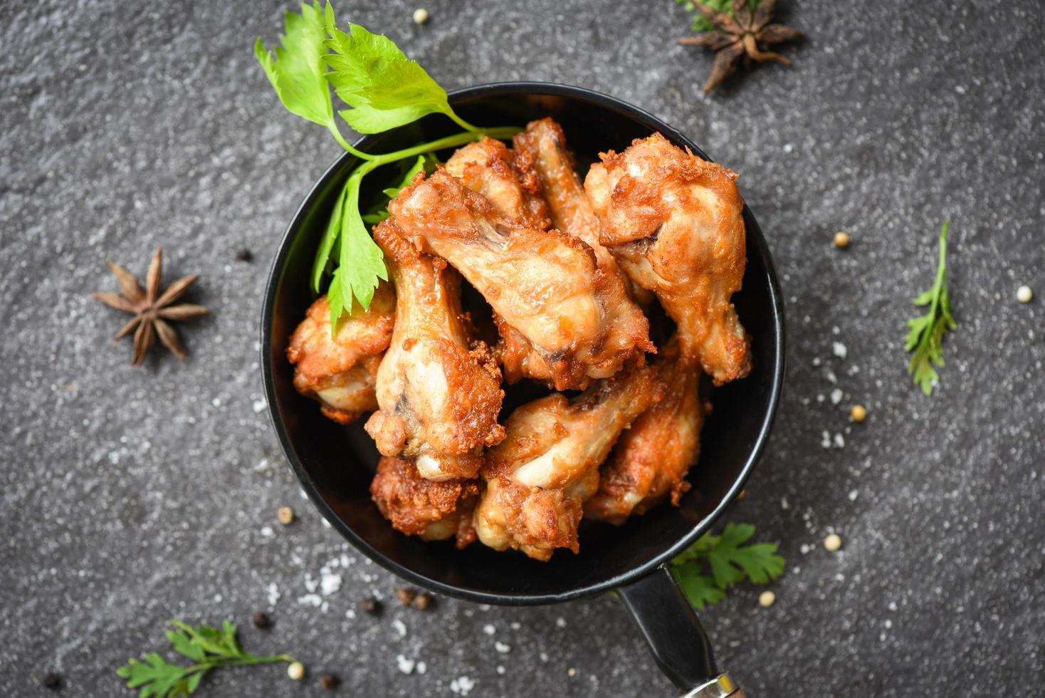 barbacoa de alitas de pollo al horno - barbacoa de alitas de pollo fritas en una sartén negra con hierbas y especias foto