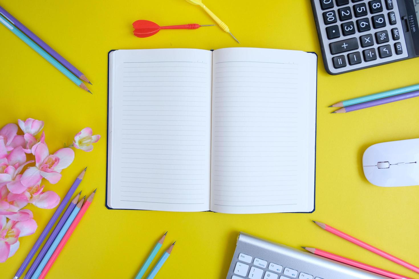 Blank notebook, a pencil, and space are on top of a yellow office desk table. Flat lay, top view education concept photo