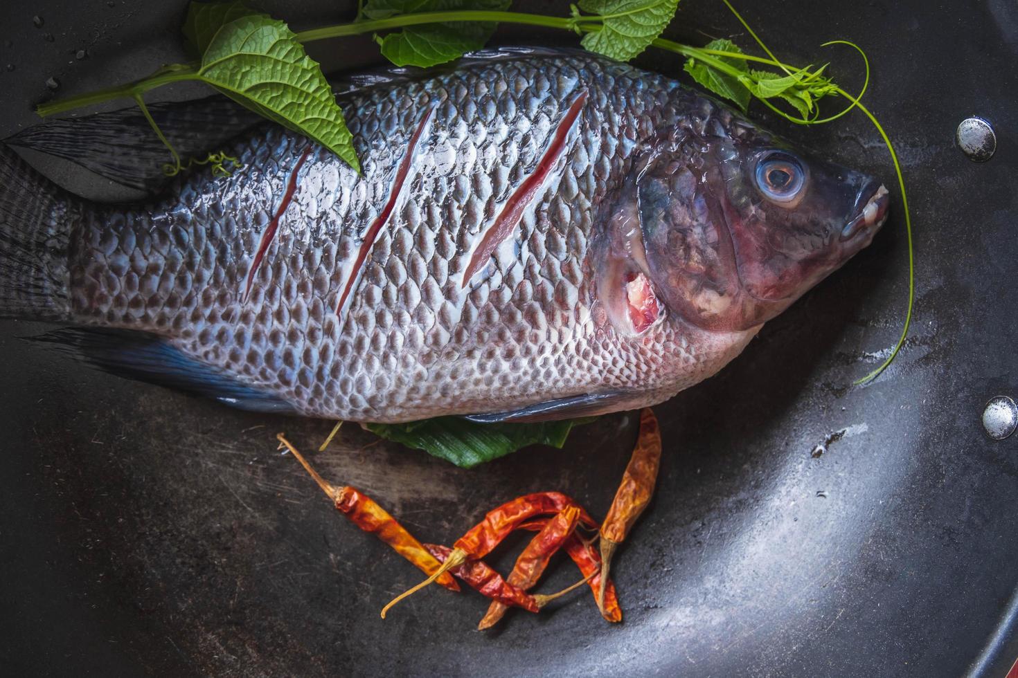 pescado fresco en una sartén y especias para cocinar foto