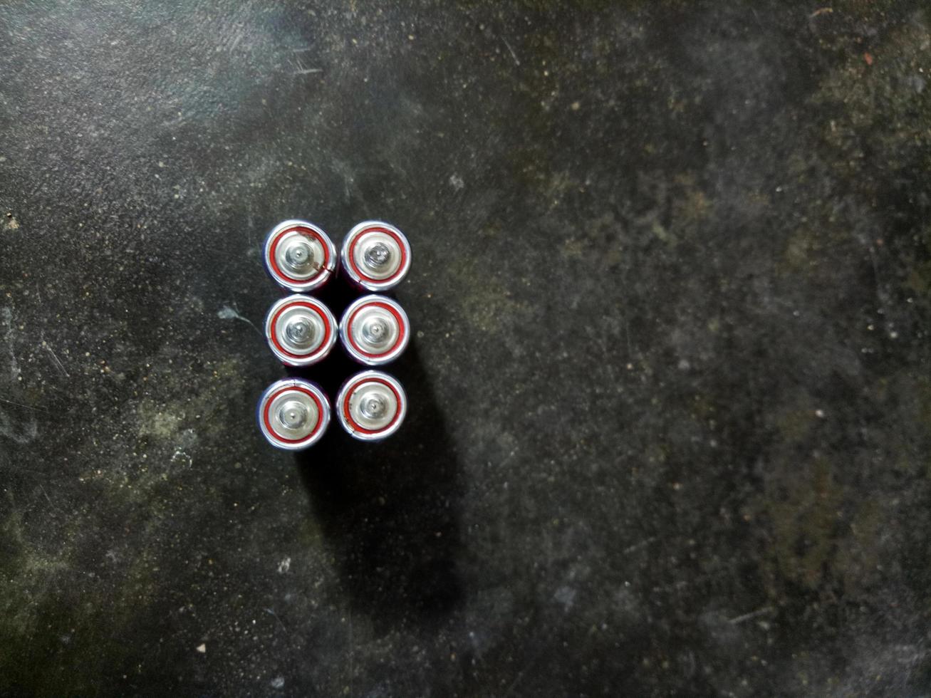 batteries lined up against a cement floor background. photo