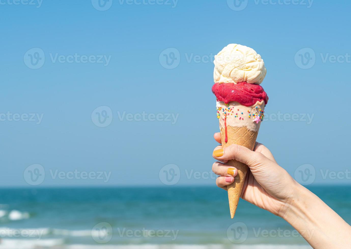 hand holding ice cream cone with blue sky background photo