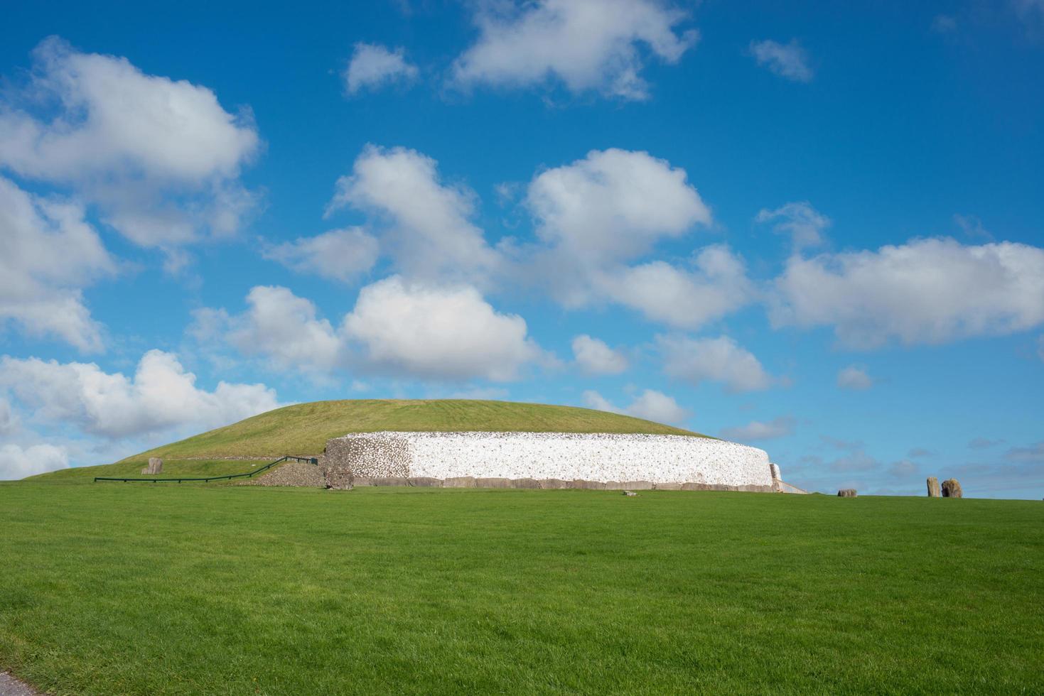 tumba del pasaje de newgrange, un sitio del patrimonio mundial de la unesco. una de las cámaras funerarias neolíticas más antiguas de europa. cielo azul con algunas nubes. foto