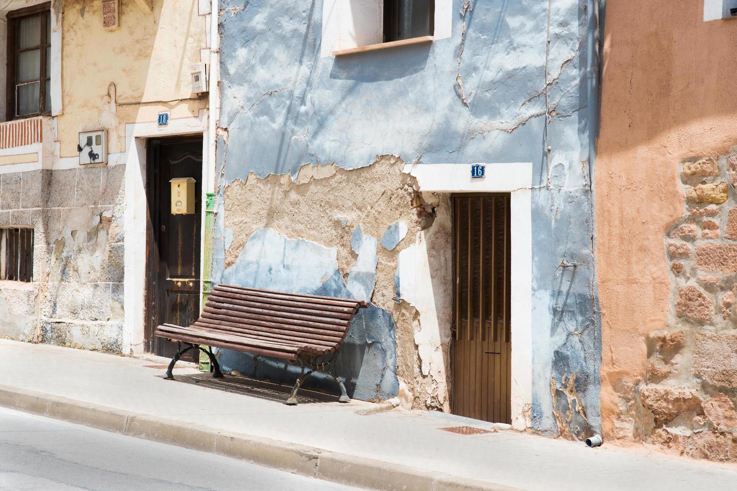 fachadas coloridas en un pueblo español en verano. banco de madera frente al azul. foto