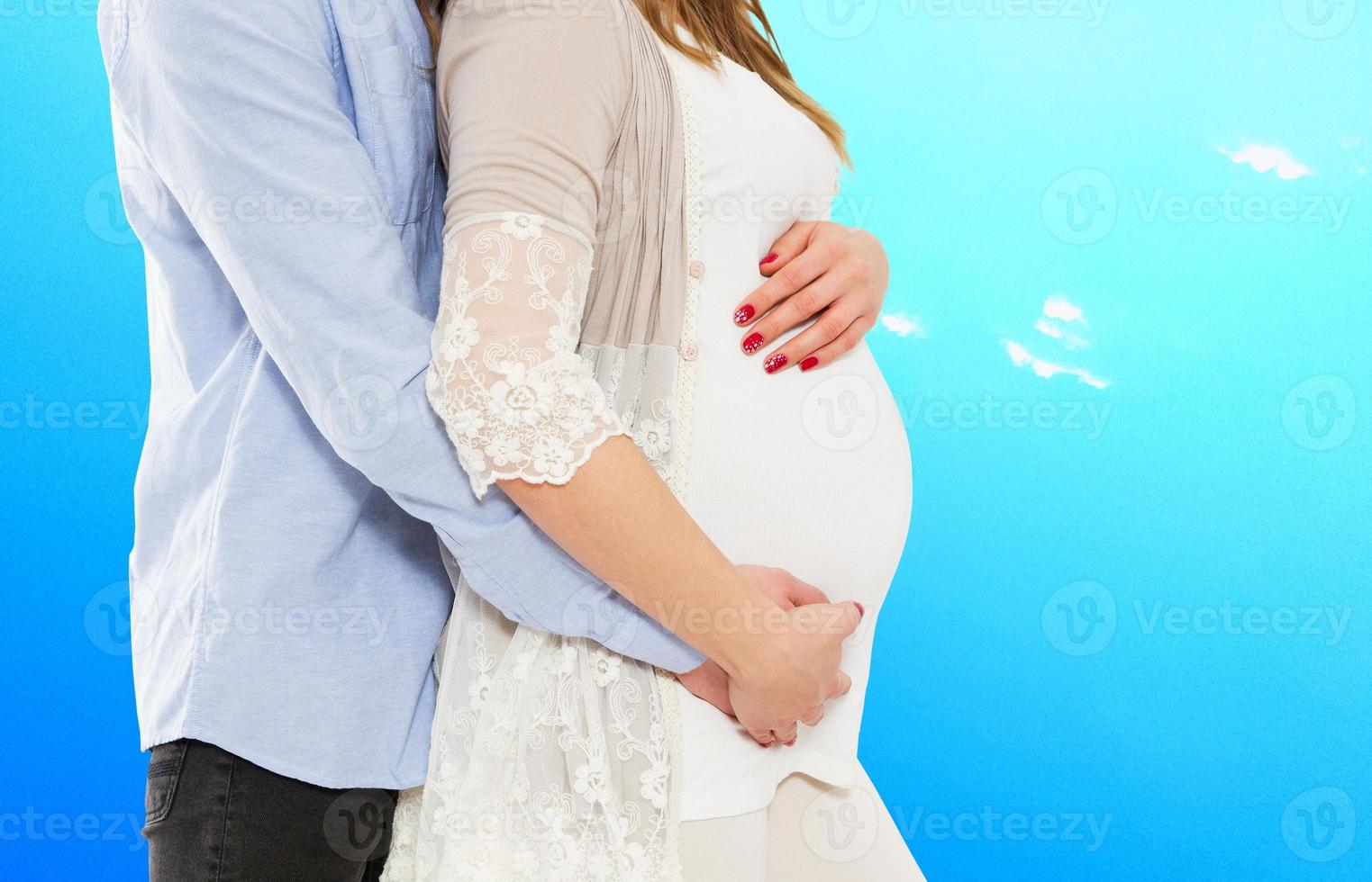 retrato de una pareja joven esperando al niño aislado de fondo azul, una pareja joven y atractiva madre embarazada y un padre feliz, una hermosa pareja joven esperando un bebé foto
